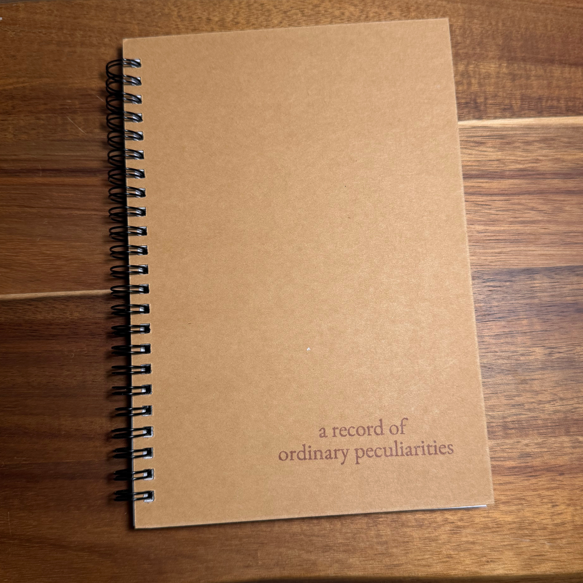 A Record of Ordinary Peculiarities — Kraft Spiral Notebook